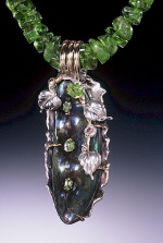 A black rock made into a necklace with green stones as the chain,