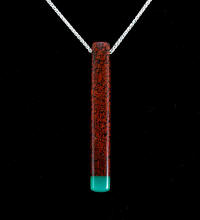 A long red and turquoise rock pendent on a silver chain.